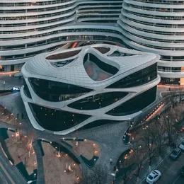 Eine Wissenschaftlerin und ein Wissenschaftler arbeiten hinter einer Glasfassade und mischen Chemikalien mit Großgeräten.